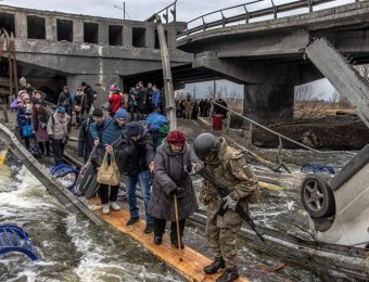 Pessoas atravessam a ponte destruída enquanto fogem da cidade da linha de frente de Irpin, região de Kiev.